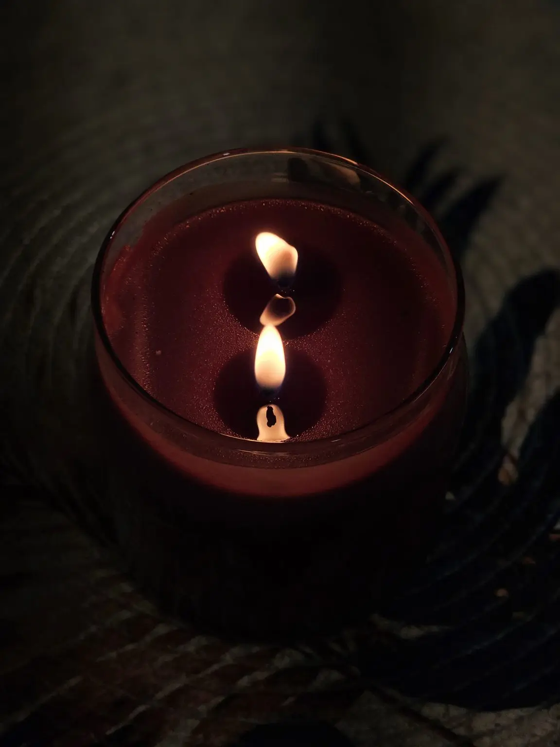 A candle glowing softly beside a closed diary on a dark table